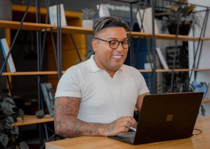 A employee sat at a table on a laptop smiling