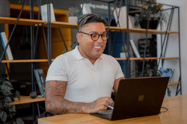 A employee sat at a table on a laptop smiling