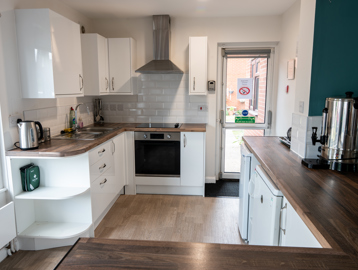 Communal kitchen with white cupboards and fire exit
