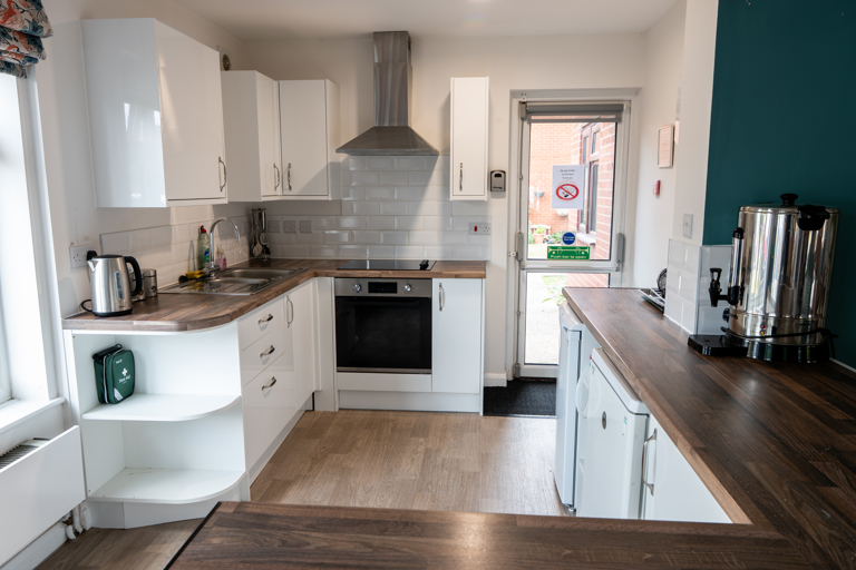 Communal kitchen with white cupboards and fire exit