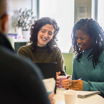 Corporate employees sitting at a table looking at a laptop
