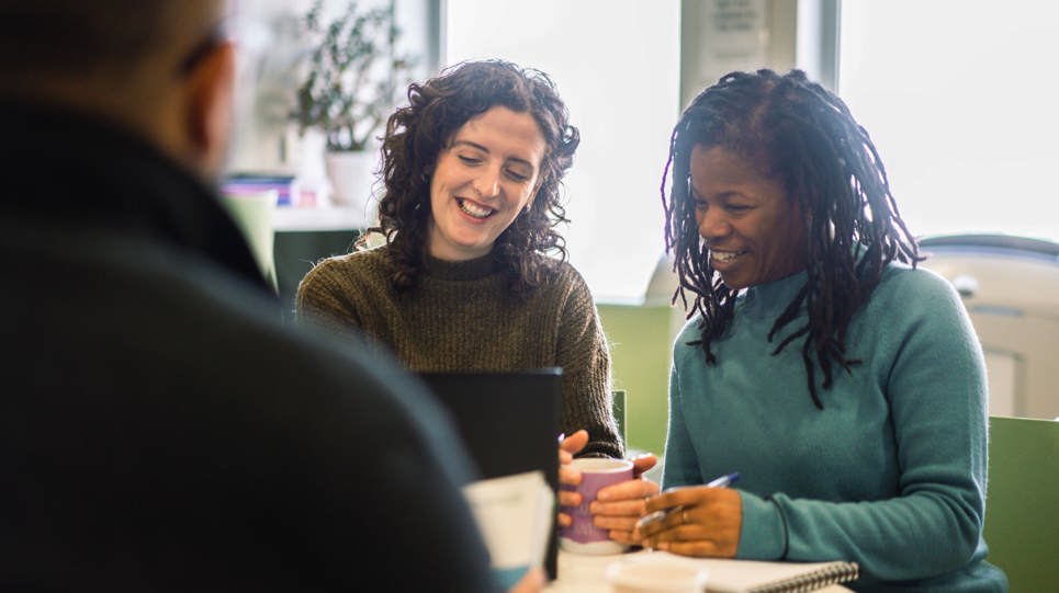 Corporate employees sitting at a table looking at a laptop