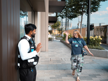 Resident Jane waving to a Security Guard in White City Living as she walks away from Minterne Apartments