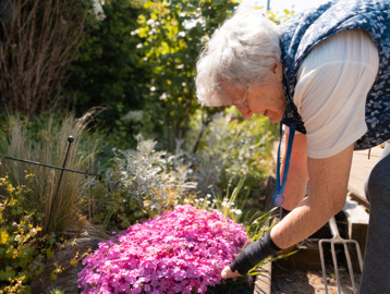 A female resident tending to some flowers in one of St Crispin's gardens