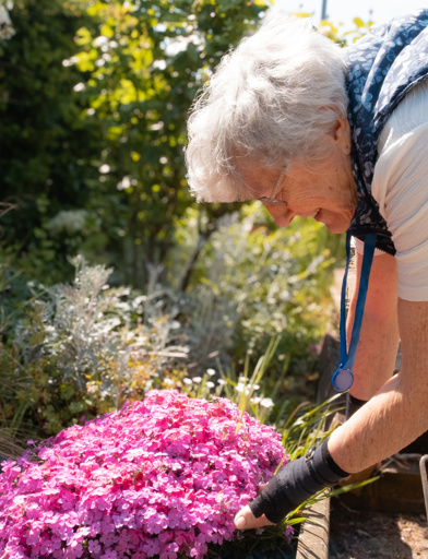 A female resident tending to some flowers in one of St Crispin's gardens 