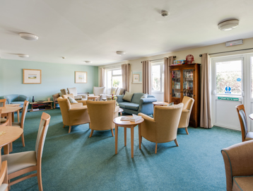 Residents' lounge with soft seating and coffee tables and a book shelf