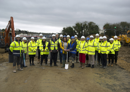 Housing 21 employees along with the Leader of Vale of White Horse Council and District councillor with key representatives stood outside on muddy ground with a spade, wearing high vis jackets and hard hats