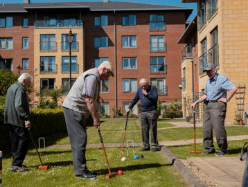 A group of male residents enjoying a game of croquet in the gardens