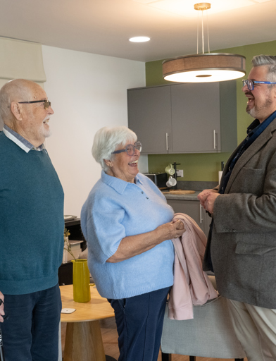 Residents laughing and talking with a Housing 21 representative inside a flat  