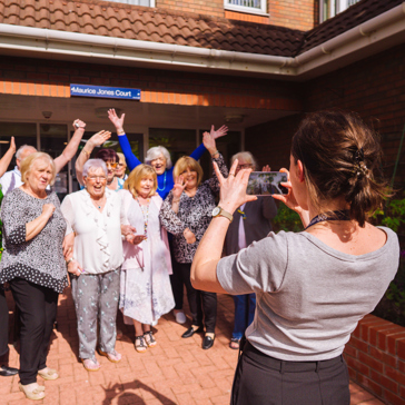 Group picture of residents having their photo taken smiling with their arms in the air