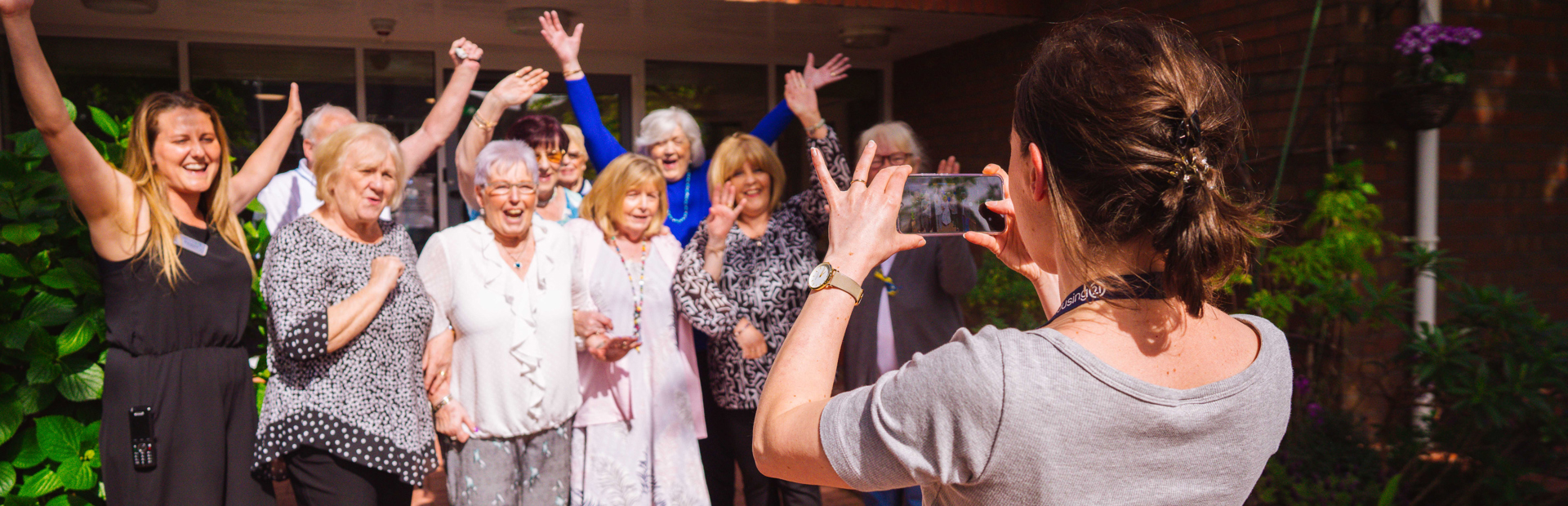 Group picture of residents having their photo taken smiling with their arms in the air
