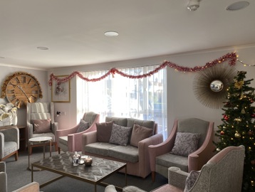 Residents' lounge with soft seating and coffee tables decorated for Christmas