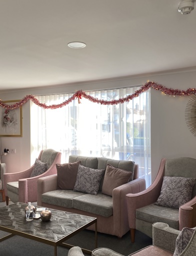 Residents' lounge with soft seating and coffee tables decorated for Christmas 