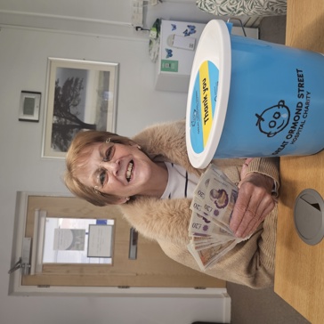 Smiling lady holds cash and charity bucket