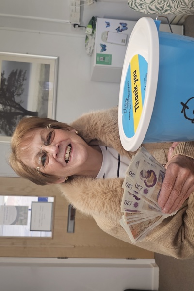 Smiling lady holds cash and charity bucket