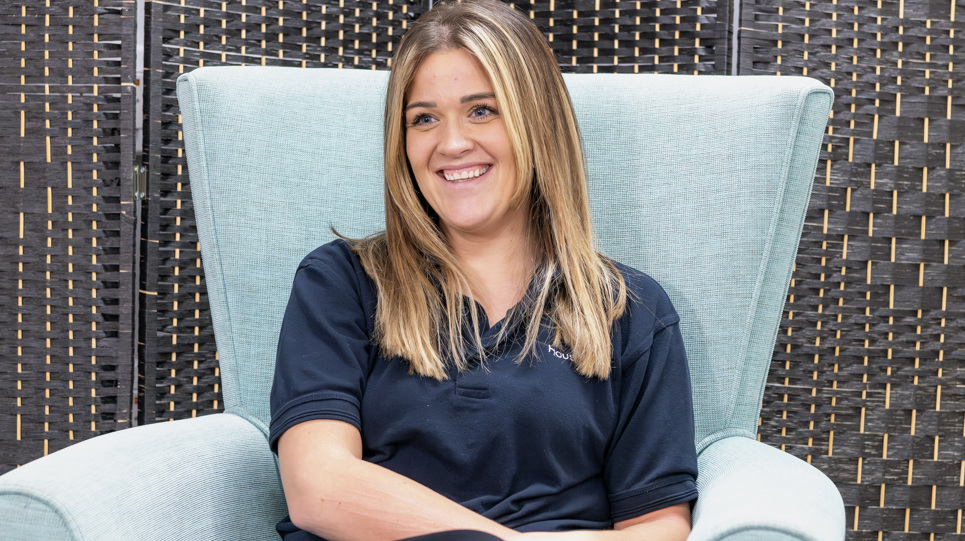 A Housing 21 employee smiling whilst sitting in a chair