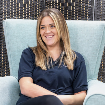 A Housing 21 employee smiling whilst sitting in a chair