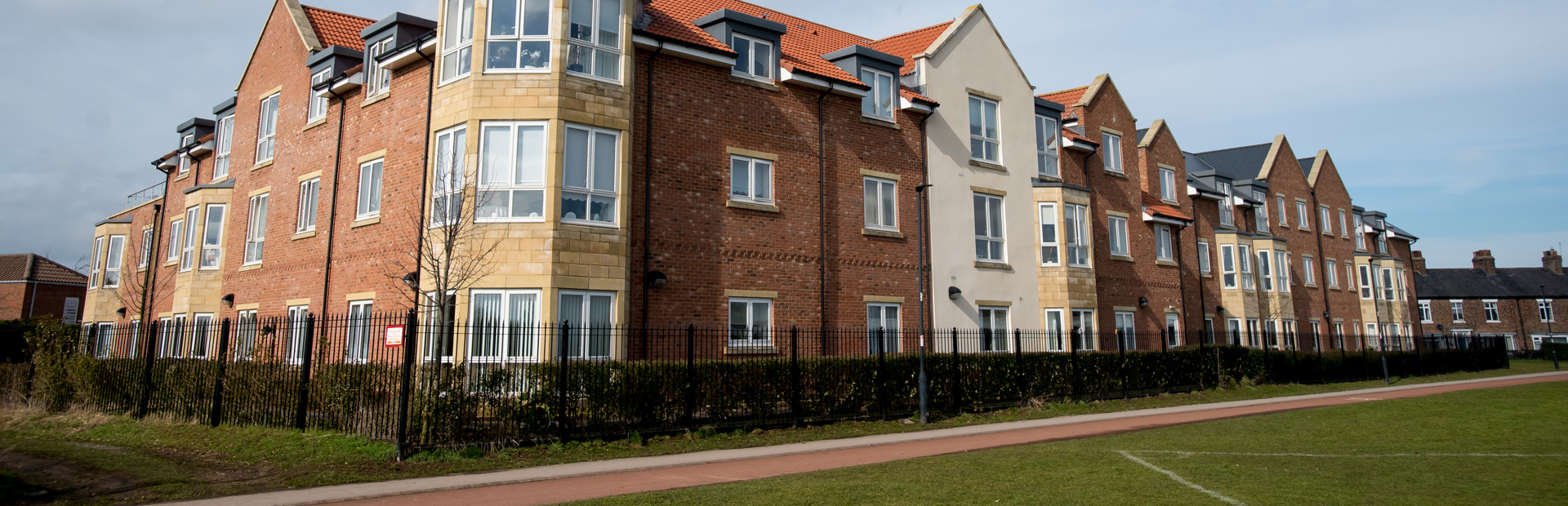 Grassed area and railing alongside the building of Meadowfields