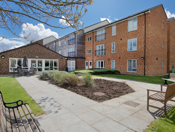 Rear garden area with patio and benches surrounding a central bedding section