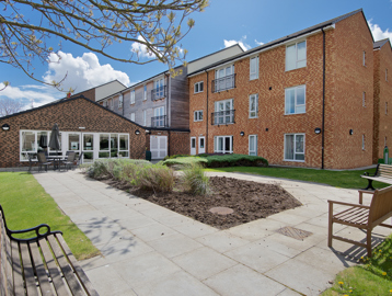 Rear garden area with patio and benches surrounding a central bedding section