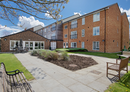 Rear garden area with patio and benches surrounding a central bedding section