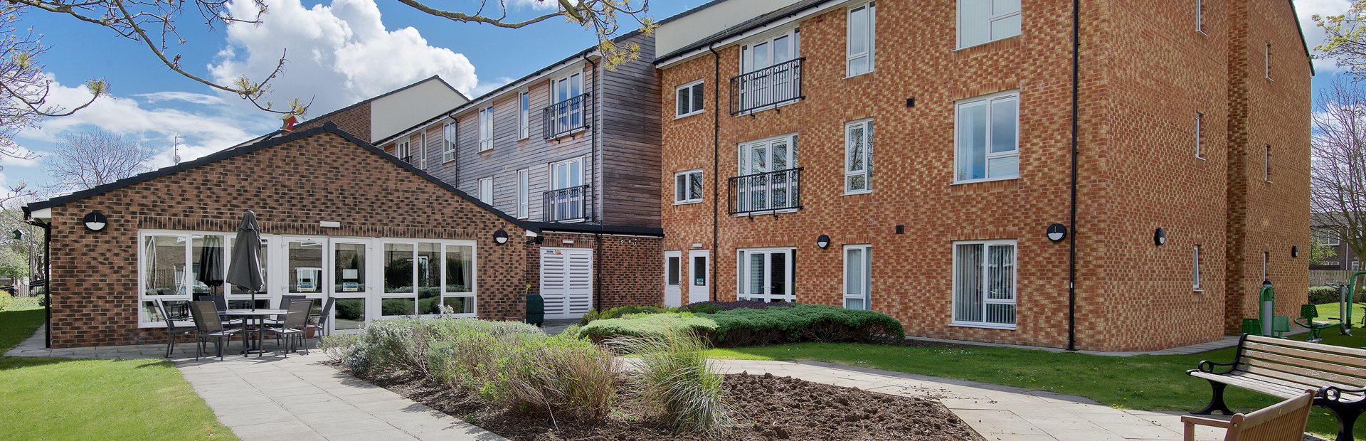 Rear garden area with patio and benches surrounding a central bedding section
