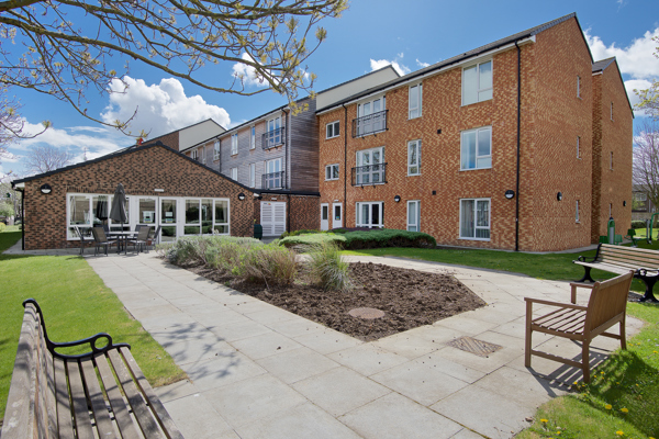 Rear garden area with patio and benches surrounding a central bedding section