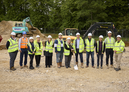 A team of construction professionals wearing high vis and holding a shovel gather at the development site of Bulmer House to mark the ground breaking ceremony