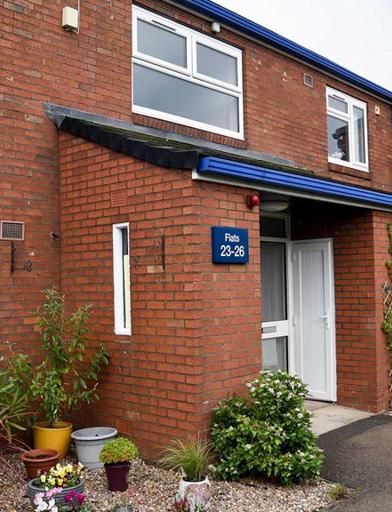 An outside photo of an apartment at Goodman Court with front door, plants and ornaments on display 