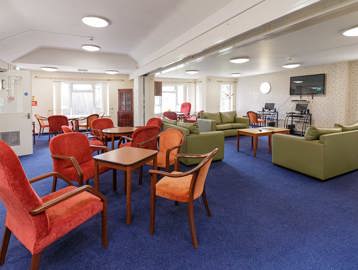 Communal lounge with seating and tables, a large wall-mounted TV and communal computers