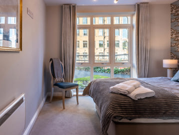 Inside the show home bedroom with double bed and side chair