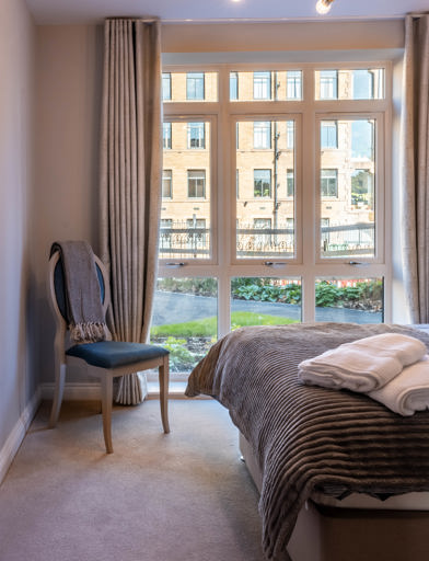 Inside the show home bedroom with double bed and side chair 