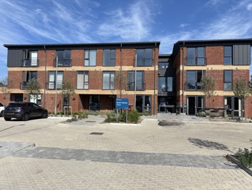 Outer building of South Hayling Court with a blocked pathed car park at the front with plants