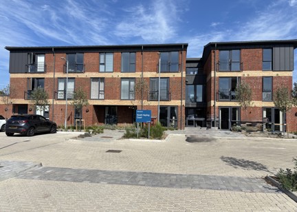 Outer building of South Hayling Court with a blocked pathed car park at the front with plants