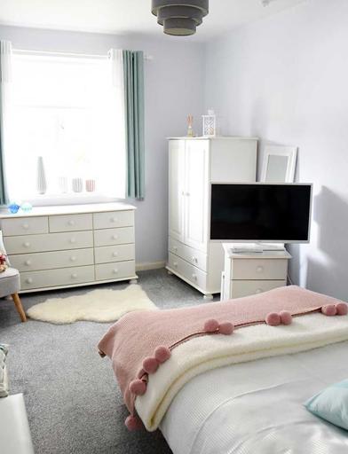 A photo of a single bedroom at Goodman Court with a bed, TV, storage units and bright window 