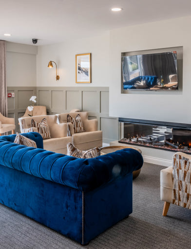 The residents' lounge with large soft seating, fireplace and wall-mounted TV 