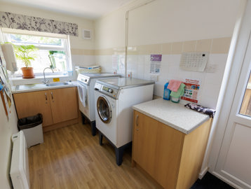 A small room with a washing machine, dryer and sink.