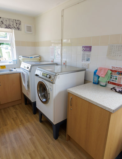 A small room with a washing machine, dryer and sink. 