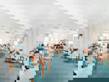 Communal lounge area with chairs and coffee tables around the edge