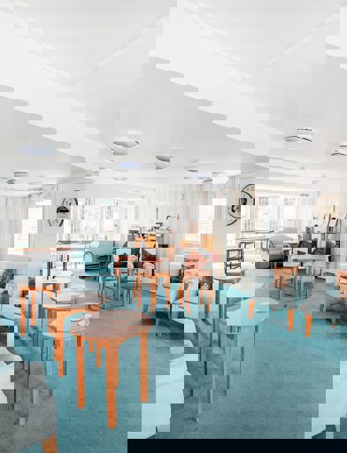 Communal lounge area with chairs and coffee tables around the edge 