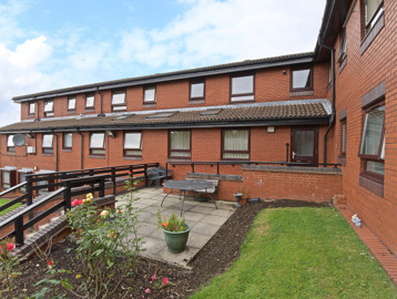 Raised patio area with seating, flowers and small grass patch