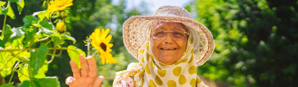 Resident in a garden smiling holding a flower