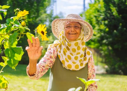 Resident in a garden smiling holding a flower