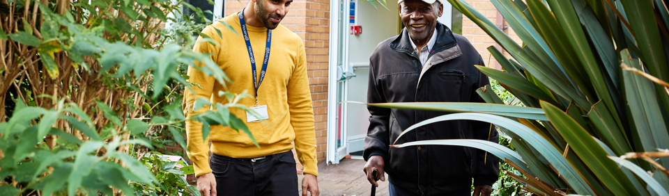 Resident walking in a garden with an employee 