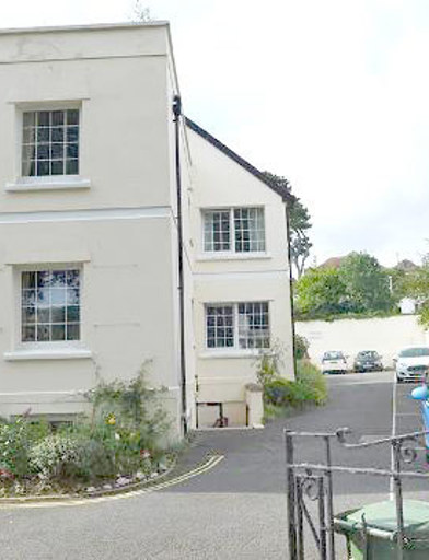 A sideview of the outside of the scheme with cars parked alongside 