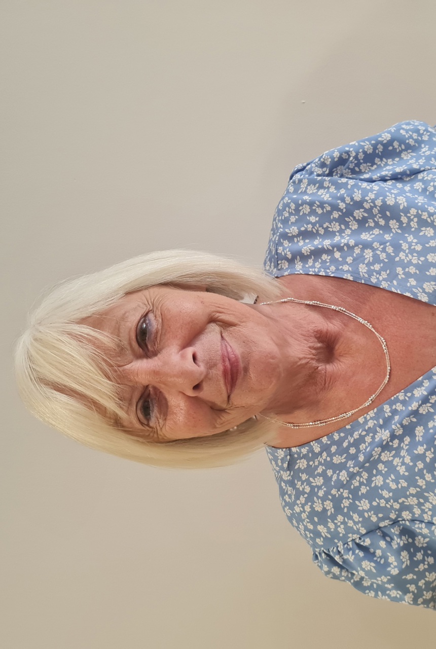 A close-up headshot of a female resident in a blue and white flowery dress