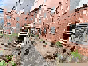 Pathway alongside the outside of the building lined by potted plants