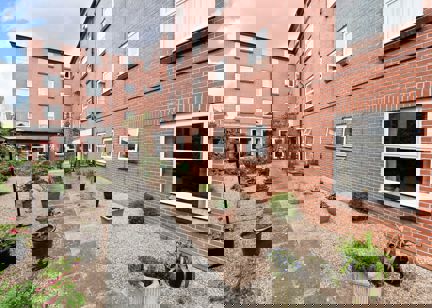 Pathway alongside the outside of the building lined by potted plants