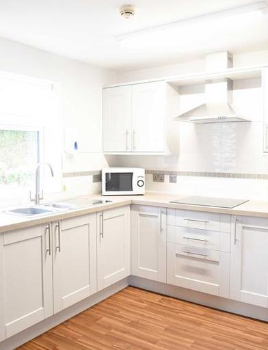 A photo of a modern, white kitchen in an apartment at Goodman Court 