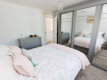 A double bed in the centre of the room with a wardrobe to the foot of the bed and a chest of doors by the entrance